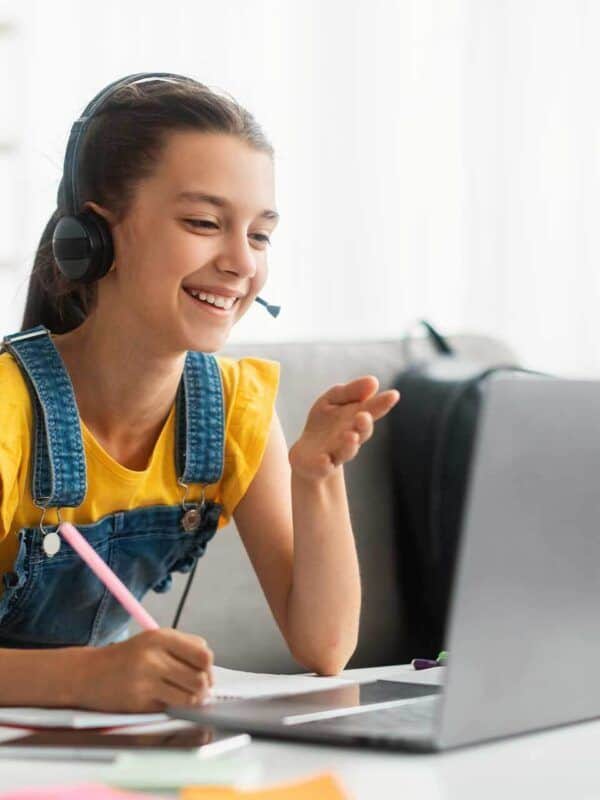 Online girl student attending Bradford International Virtual School virtual class, using headset and laptop for remote learning