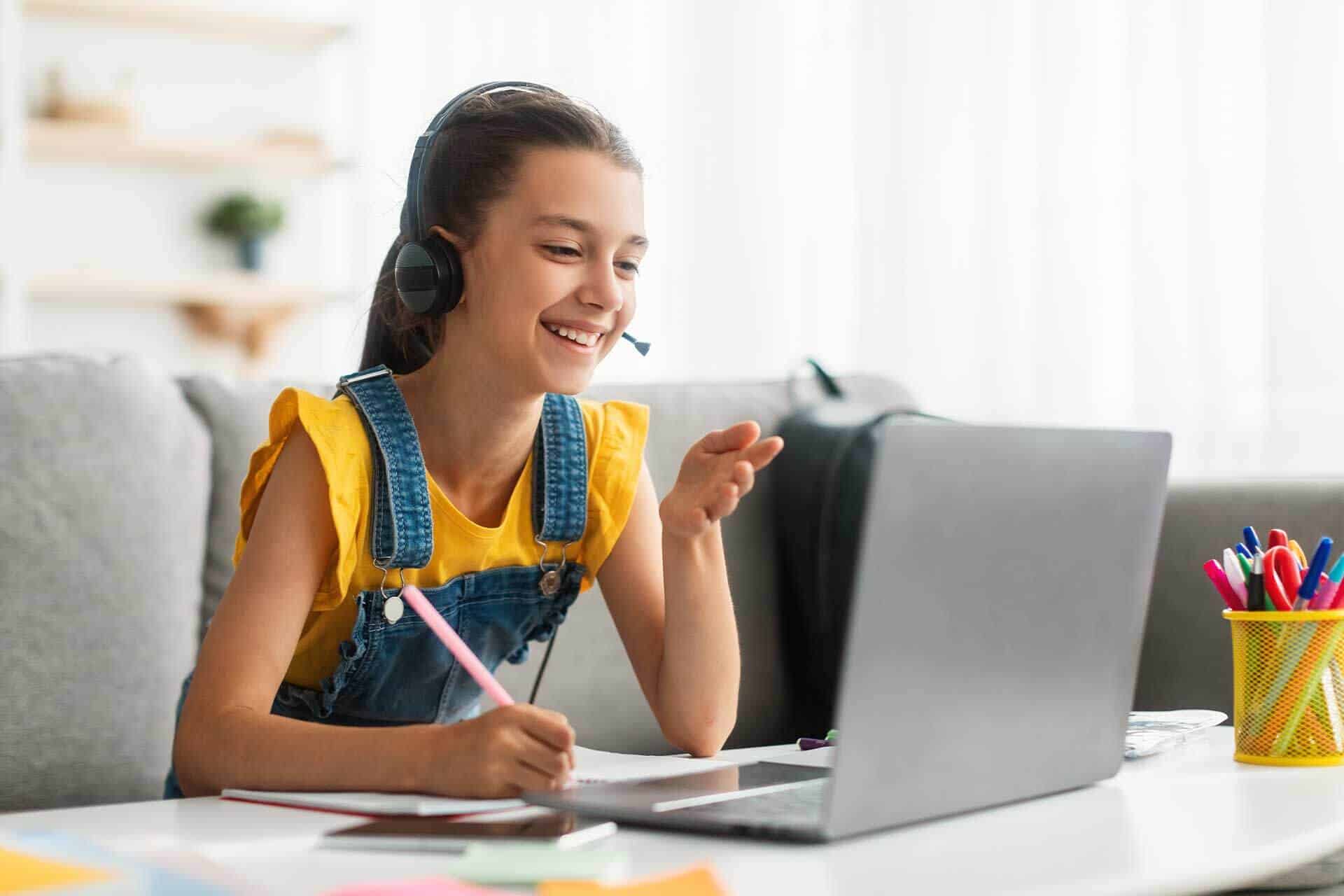 Online girl student attending Bradford International Virtual School virtual class, using headset and laptop for remote learning