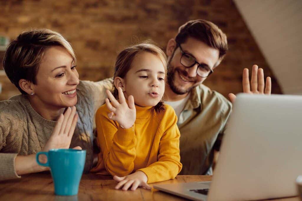 A smiling family engaging in a virtual learning session on a laptop at home, exemplifying Bradford International Virtual School offerings.